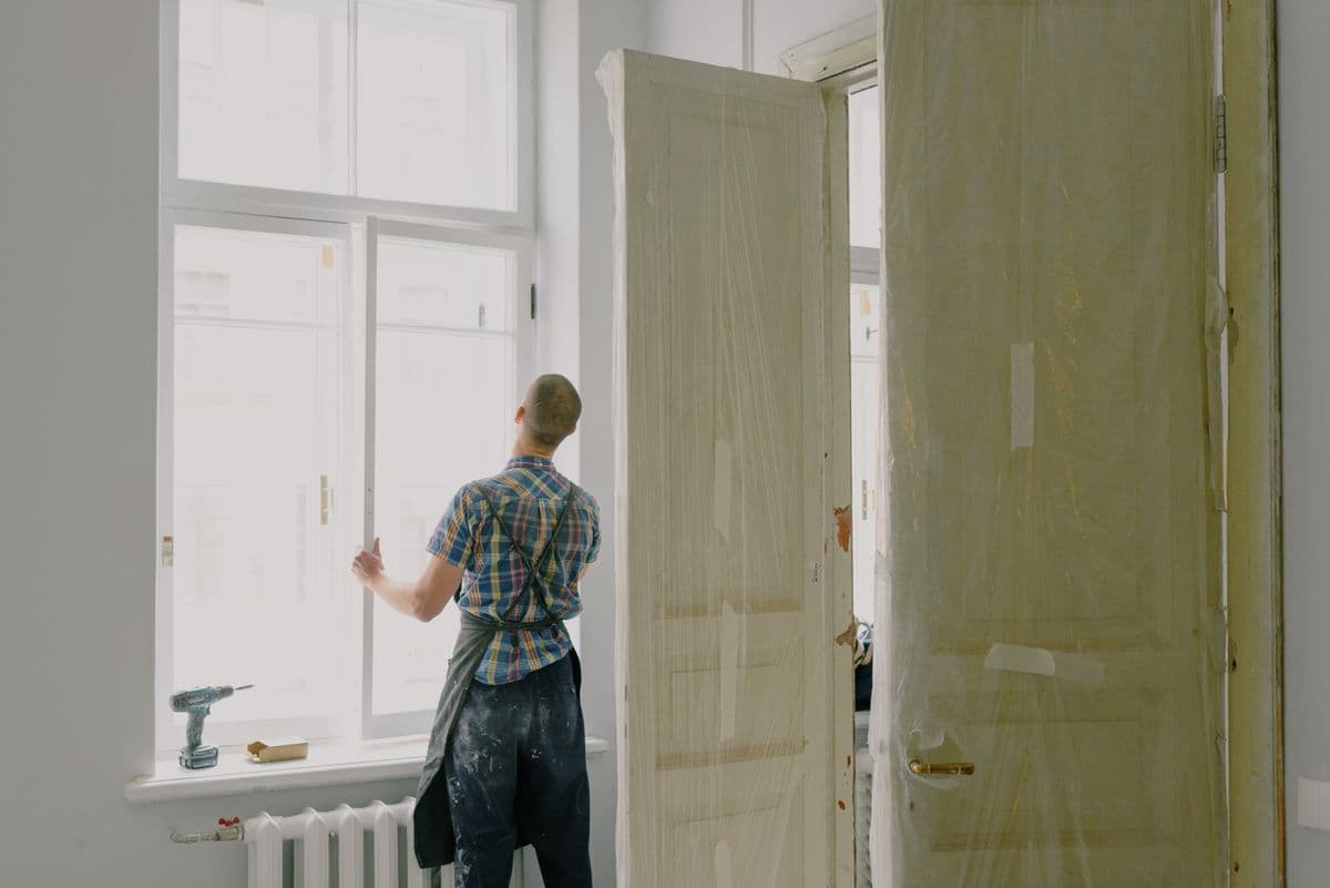 Handwerker beim Fenstertausch in einem Altbauzimmer während der Sanierung