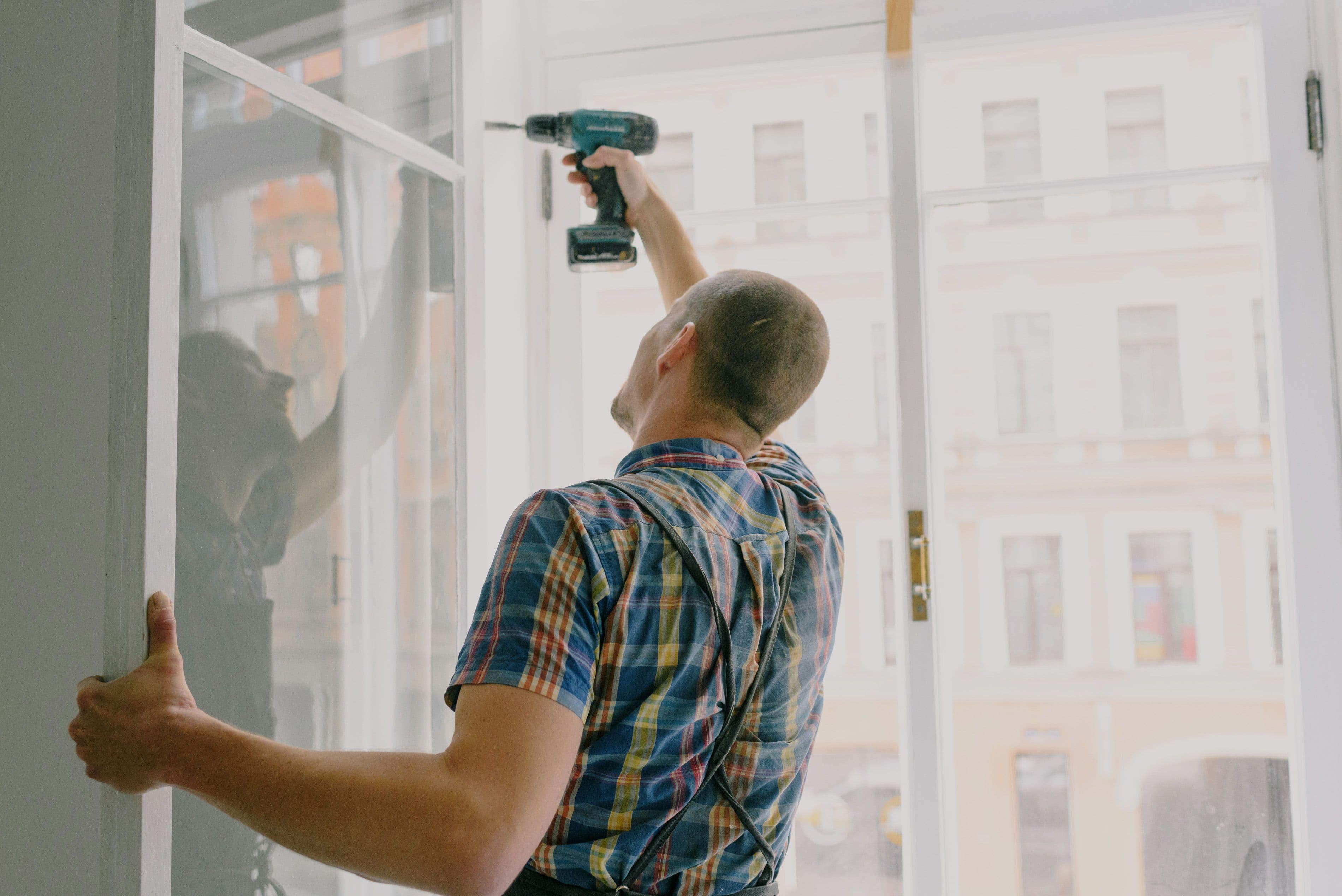 Handwerker befestigt einen Fensterrahmen mit einem Akkuschrauber